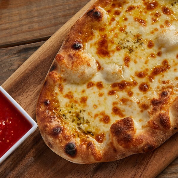 Wood-fired garlic bread with melted cheese and herbs, served with a side of marinara sauce.
